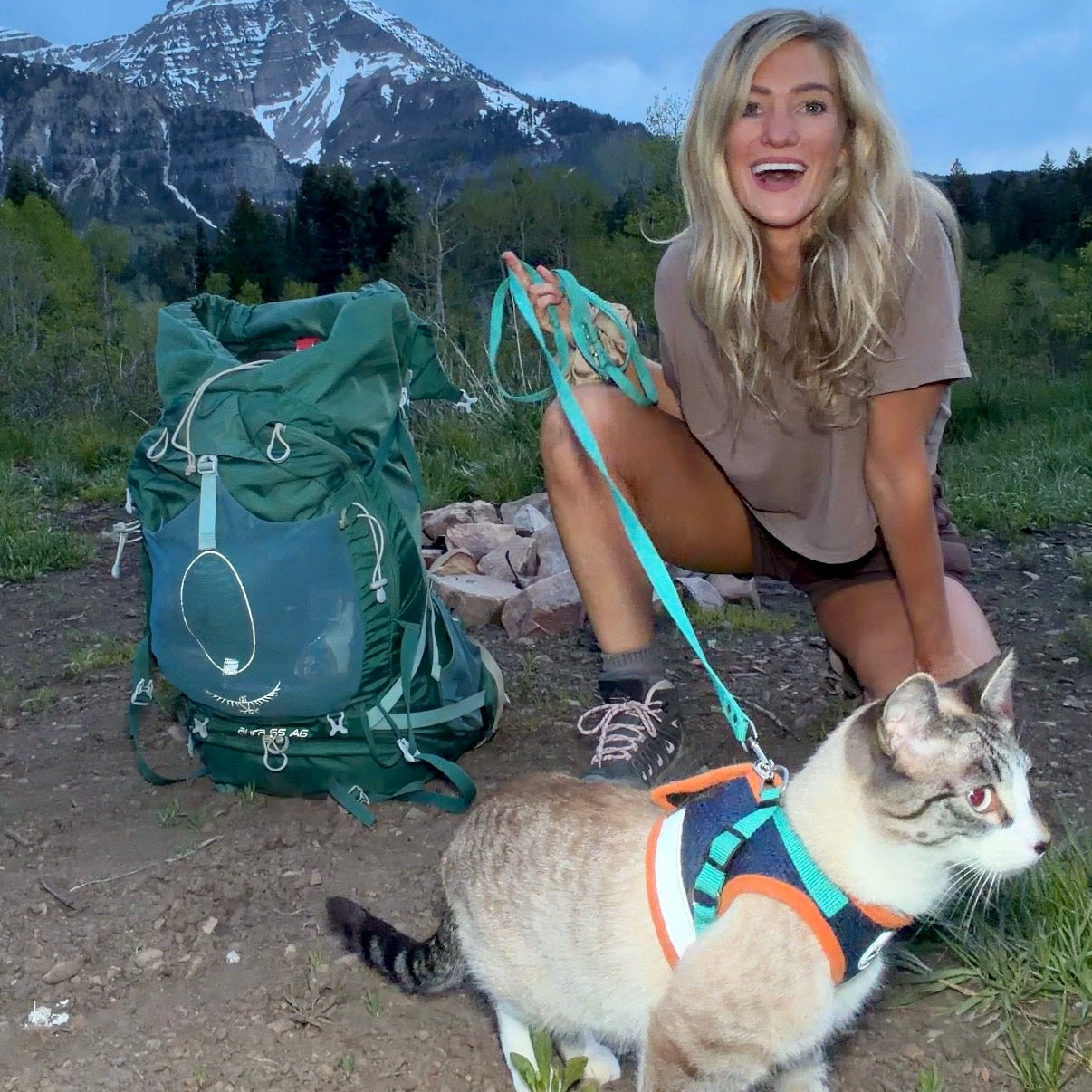 Woman with a cat on a leash in a mountainous area